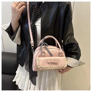 Detail of pink shell bag featuring lace trim, bow accents, and checkered ribbon on handle