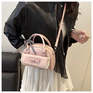 Pink crossbody bag featuring lace trim, bow detail, and checkered ribbon on the handle