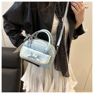 Detail of light blue handbag with lace trim, bow decoration and checkered handle ribbon