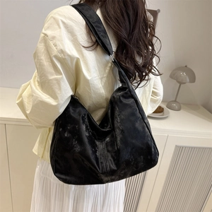 Sac fourre-tout noir minimaliste porté à l'épaule avec un drapé élégant et texturé
