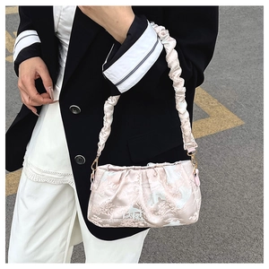 Close-up of light pink satin pleated cloud bag with traditional landscape pattern detail