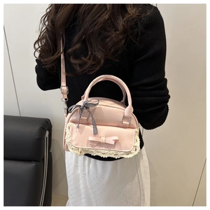 Detail of pink faux leather handbag with lace trim and black plaid bow tie decoration