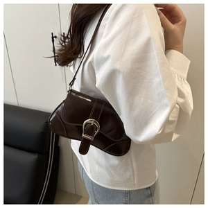 Close-up of chocolate brown baguette bag with silver metal buckle on leather seat