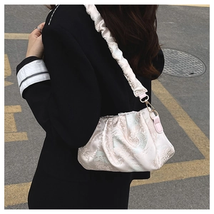 Detail of the elegant floral embroidery and pleated strap on this silk shoulder bag