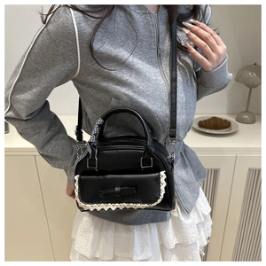 Detail of black shell bag with white lace trim and bow ribbon in daily setting