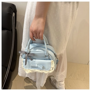 Detail of light blue seashell bag featuring lace trim and a small checkered bow