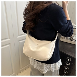 Détail du sac hobo en cuir blanc crème avec logo imprimé et texture lisse brillante