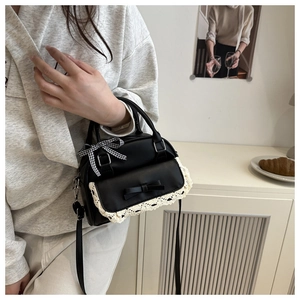 Detail of black shell bag with white lace trim, bow decoration and gingham ribbon handle