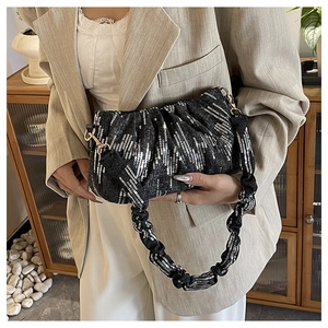 Detail of black pleated underarm bag featuring shimmering silver sequins and scrunchie strap