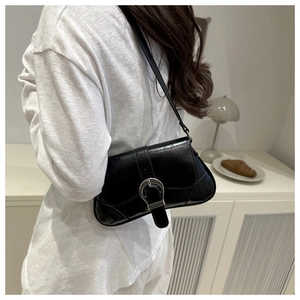 Detail of a black glossy PU leather underarm bag with silver horseshoe buckle and slim strap