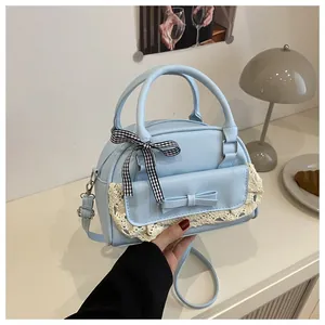 Detail of light blue shell bag featuring lace edges, a bow, and checkered ribbon decor