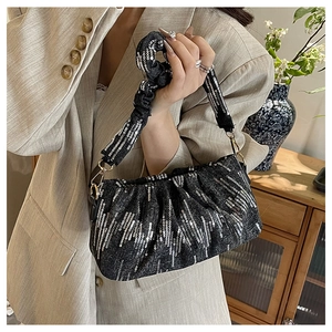 Detailed view of black sequined underarm bag with pleated handle and metal buckle hooks