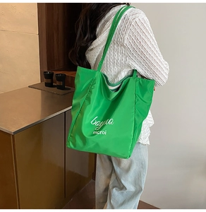 Detail of green nylon tote bag featuring logo print and spacious shoulder straps