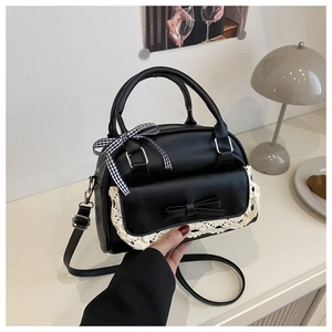 Detail of black shell bag with lace trim and black-and-white checkered bow accent