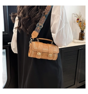 Detail of retro caramel barrel bag featuring white rivet trim and ethnic wide strap