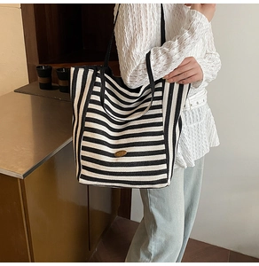 Close-up of black and white striped tote bag with elegant gold emblem and leather strap