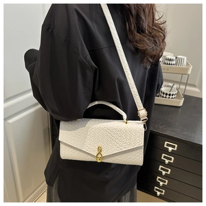 Detail of white crocodile pattern shoulder bag with golden infinity symbol metal clasp