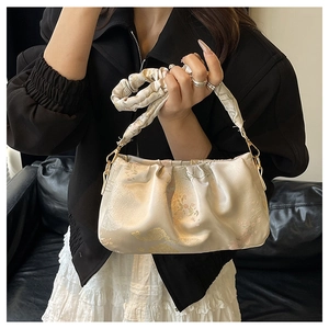 Detail view of beige floral jacquard fabric and pleated design on shoulder bag