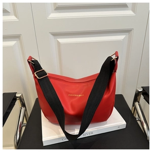 Vue détaillée d'un sac cabas en cuir rouge avec lettres dorées et bandoulière noire