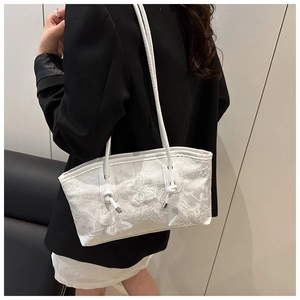 Detail of white shoulder bag featuring delicate butterfly embroidery and knotted straps