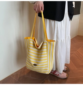Detail of yellow and white striped canvas tote bag with retro oval metallic logo patch