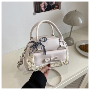Detail of cream leather shell bag with lace trim, leather bow, and checkered ribbon decoration