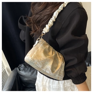 Detail of off-white jacquard fabric cloud bag with vintage gold floral pattern texture