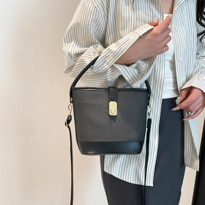 Chic black bucket bag with woven texture, leather trim and gold twist lock closure