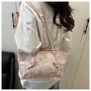 Detail of pink lace tote bag featuring 3D butterfly appliques and knotted shoulder strap