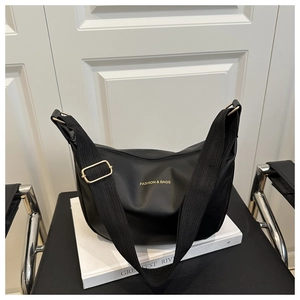 Détail de la sacoche noire avec boucles dorées et logo posée sur une chaise chic