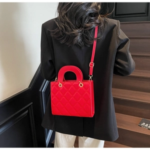 Dettaglio di una borsa trapuntata rossa con finiture dorate sulla spalla della modella