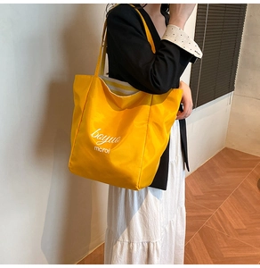Close-up of bright yellow tote bag with printed text and striped lining on shoulder