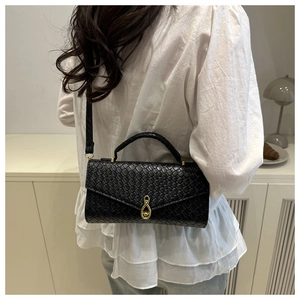 Detail of black crocodile texture shoulder bag with gold teardrop buckle and shoulder strap