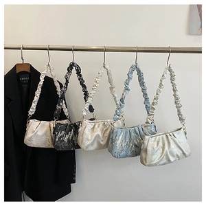 Detail of satin cloud bags with pleated straps and floral embroidery hanging on a rack