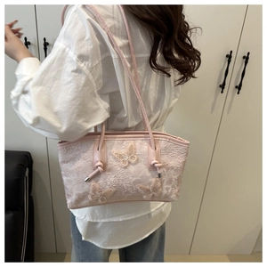 Detail of pink lace tote bag featuring floral texture and 3D butterfly embellishments