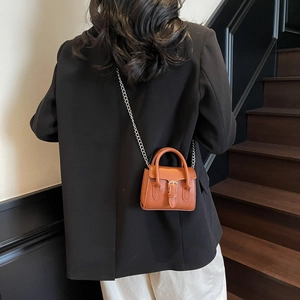 Petit sac carré marron minimaliste avec bandoulière chaîne argentée porté par modèle