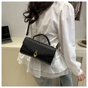 Detailed view of black woven texture handbag featuring a golden teardrop metal clasp