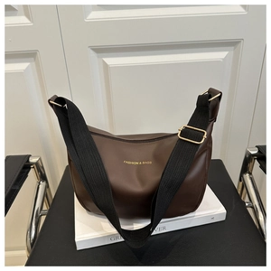 Détail d'un sac cabas en similicuir marron avec bandoulière noire et boucle dorée