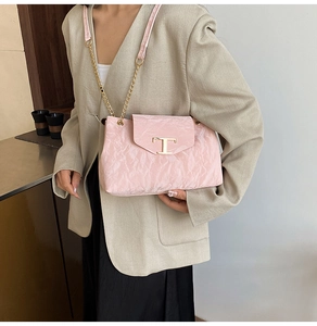 Borsa rosa plissettata con logo T dorato e catena, indossata su un blazer beige