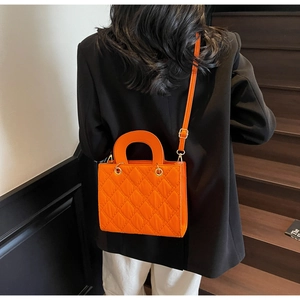 Vista posteriore di una borsa trapuntata arancione vivace con un blazer nero