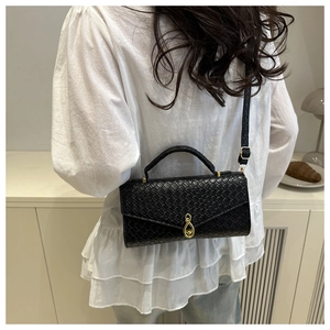 Detailed back view of a black embossed crossbody bag worn by a model in a modern home