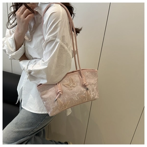 Detail of pink lace tote bag with 3D butterfly embroidery shown on a shoulder