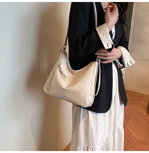 Detail view of cream-colored hobo bag with decorative vertical zipper and adjustable strap