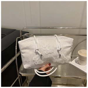 Close-up of white lace tote bag featuring 3D butterfly embroidery and twisted rope handle