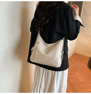 Chic off-white leather hobo bag with fringe details shown on a model's shoulder