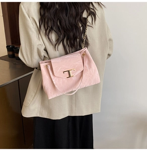 Dettaglio della borsa rosa lucida con chiusura a T dorata e tracolla a catena in metallo