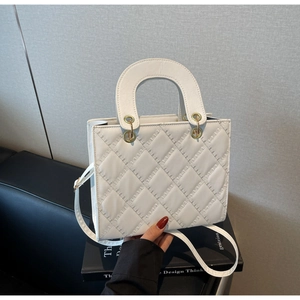 Dettaglio della borsa trapuntata bianca con hardware dorato e manico superiore elegante