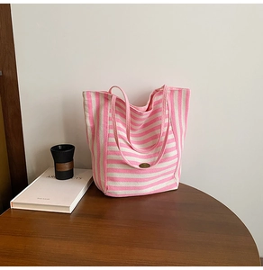 Detailed shot of pink and white striped canvas tote bag with oval vintage metal logo tag