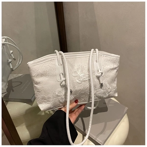 Detail of elegant white lace embroidery and floral patterns on a luxury shoulder bag
