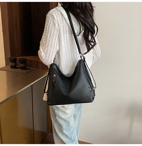 Macro view of the black leather hobo bag showing side zipper detail and metal hardware buckle